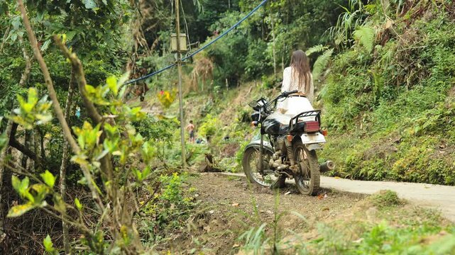 Traveler walks narrow jungle path past parked motorbike near Batad terraces