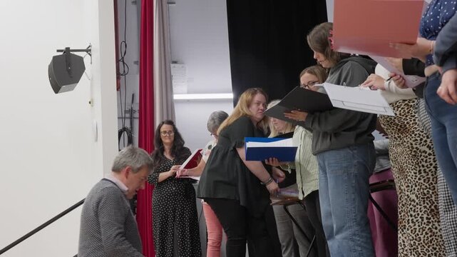 Amateur theatre performers in Prestwick, Scotland, rehearse on stage. A director provides artistic guidance to the group during a creative drama session in a local community theater hall