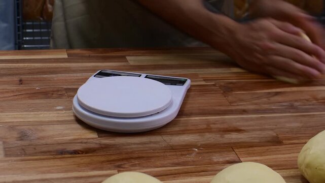 Professional baker weighing fresh bread dough portions inside a bakery
