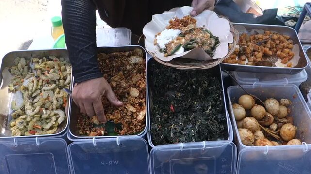 Pecel seller is serving buyers, Indonesian food made from boiled vegetables seasoned with spicy peanut sauce and palm sugar