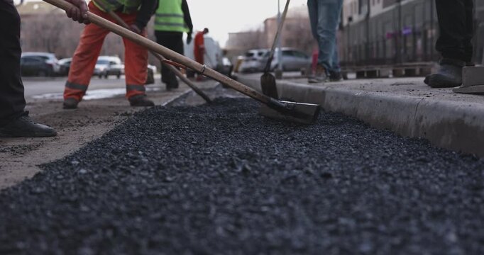 Road workers laying fresh asphalt pavement