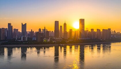 Fototapeta premium A stunning aerial view captures a vibrant cityscape bathed in the warm glow of a setting sun, reflected beautifully in the calm waters below.