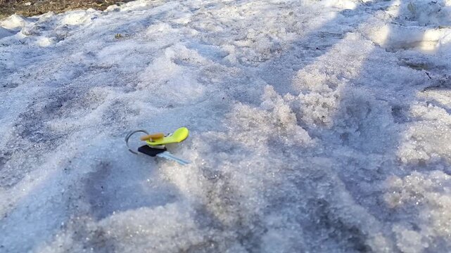 A hand picks up the lost keys to the apartment from the snow in winter. A woman found the keys on the road