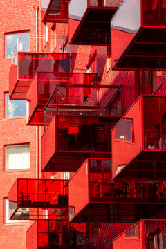 Bold red exterior architecture featuring modern apartments facade with balconies windows and geometry pattern creating strong graphic design