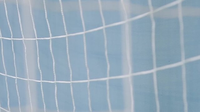 A close-up of a blue handball gate with a stretched white net in an indoor gym or sports complex.