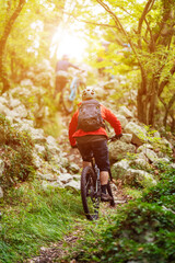 Fototapeta premium Mountain bikers riding a rocky forest trail at sunrise for outdoor adventure and fitness
