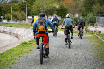 Naklejka premium Group of mountain bikers cycling on a gravel trail with backpacks and protective gear in countryside