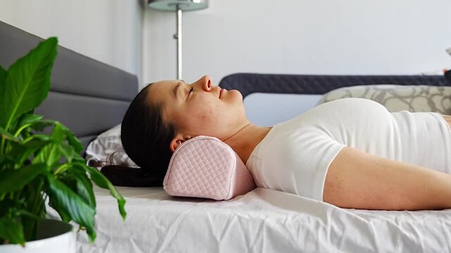 Side view of woman resting on ergonomic orthopedic pillow on bed. Calm breathing, proper neck alignment and cervical spine support for relaxation, stress relief and healthy comfortable sleep at home.