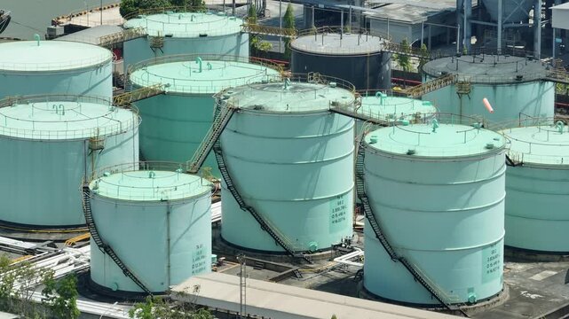 Bird&rsquo;s-eye drone view of an oil tank farm with organized infrastructure, illustrating large-scale energy storage, industrial logistics, the evolving balance between fossil fuels and green innovation.
