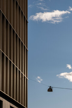Modern architecture facade of a building with vertical lines and a street lamp on cable against minimal sky for clean urban design space