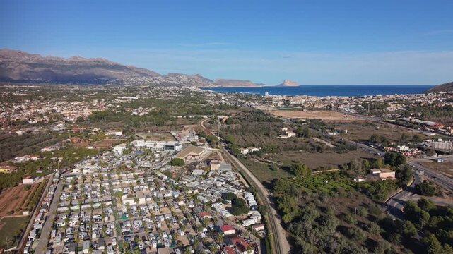 Camping Almafra high forward drone footage of whole site with sea views,Albir and Benidorm with orange groves mountains and the resorts themselves in the distance on sunny day with blue sky