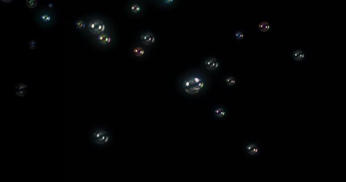 Iridescent soap bubbles float gracefully against a rich, dark backdrop, creating a truly stunning visual effect that is perfect for motion graphics, design projects, and embracing abstract