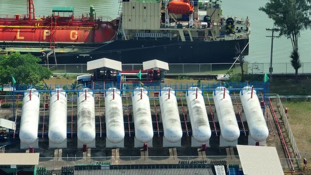 Drone perspective capturing an LPG vessel near a row of cylindrical storage tanks, reflecting modern gas supply chains, port operations, and the transition toward cleaner fuel alternatives. 4k.
