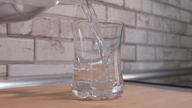 Close-up of a white effervescent painkiller tablet falling into a glass of fresh water and dissolving with bubbles. Concept for medicine, healthcare, and pharmacy.