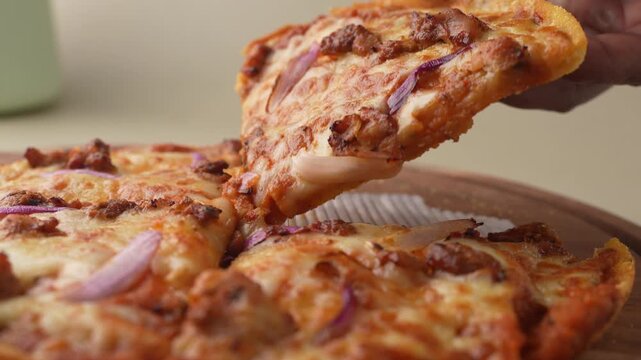 Thin crust pizza topped with chicken, cheese, and chives on a wooden plate, getting picked from table.