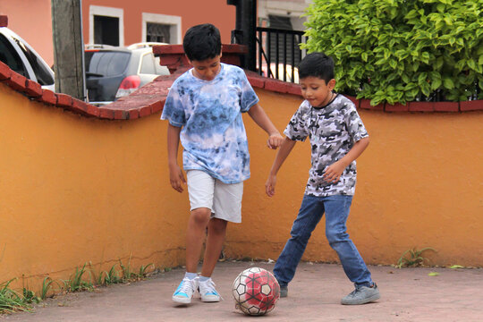 Ten-year-old Latino boys with dark skin play soccer in the street for fun and dream of becoming champions