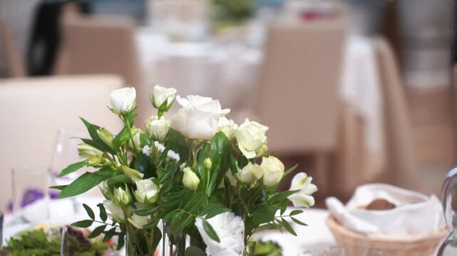 Wedding table decor with white flowers, blank card stand on white tablecloth, fabric drapery background, floral arrangement front view, with copy space. Concept wedding, ceremony, invitation, luxury