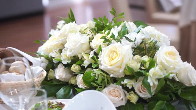 Wedding table decor with white flowers, blank card stand on white tablecloth, fabric drapery background, floral arrangement front view, with copy space. Concept wedding, ceremony, invitation, luxury