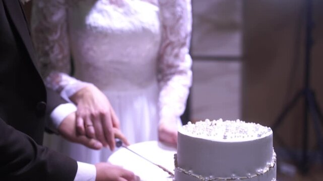 female and male hands cutting a wedding cake