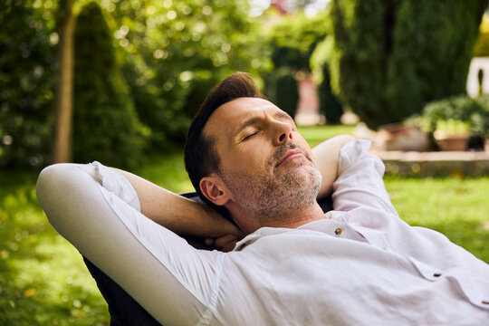 Man relaxing on sunbed napping happily in backyard outdoors