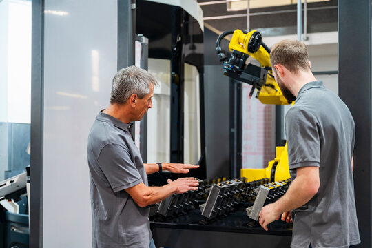 Engineers discussing in a production hall with an industrial robot