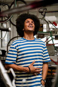 Smiling small business owner in striped shirt at urban bicycle shop