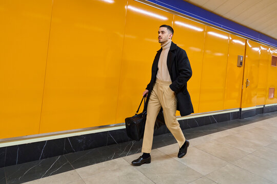 Confident businessman walking with bag in urban setting wearing coat