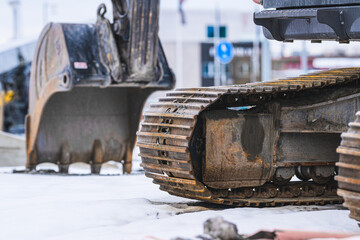 Close up of excavator steel tracks on snowy construction site in winter. © Trygve
