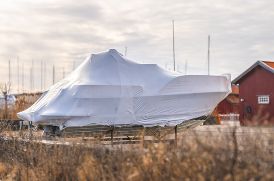 Winterized motorboat wrapped in white protective cover at marina.