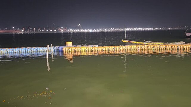 Night view of the illuminated Triveni Sangam riverfront in Prayagraj, Uttar Pradesh, India, featuring riverside lighting, temporary structures, and a peaceful pilgrimage atmosphere. Ideal for travel