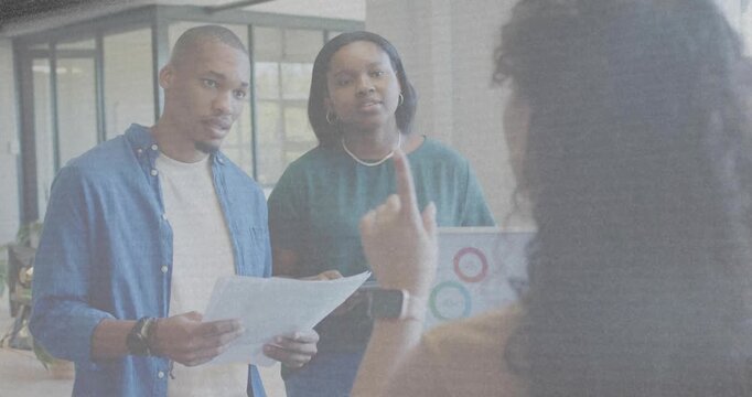 Lead gesturing, man reading papers, woman checking laptop charts, animated data guiding business