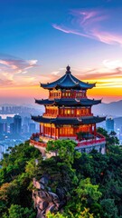 Obraz premium A stunning panoramic view showcases a traditional Chinese pagoda perched atop a lush, green mountain, bathed in the warm glow of a vibrant sunset over a sprawling cityscape.