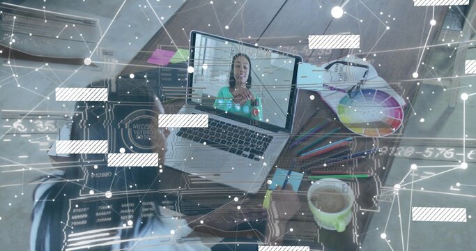 Multitasking seated woman in light top writing at home desk with phone, laptop call, color wheel