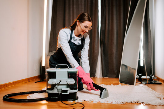 Cleaner performs wet cleaning on a carpet using a wet vacuum cleaner in a room with curtains