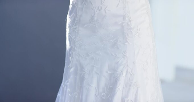 Vertical video: Rising camera revealing model touching chin, posing by wall for white lace dress