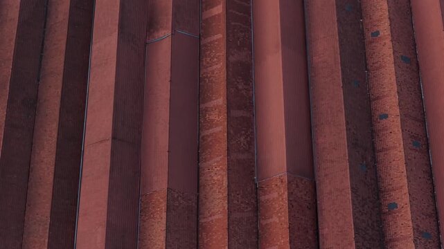Aerial view of Port wine cellars with a textured red building with multiple vertical lines creating a pattern of light and shadow, Porto, Portugal.