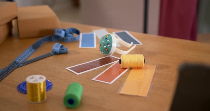 Camera pulling focus and shifting framing on wooden table, highlighting yellow spool pincushion
