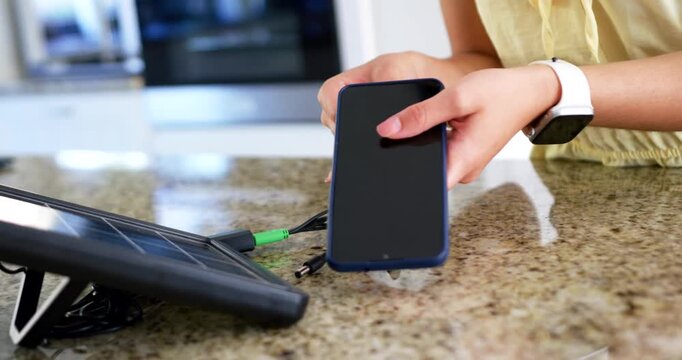 Woman choosing adapter and aligning phone on granite counter by solar panel, copy space