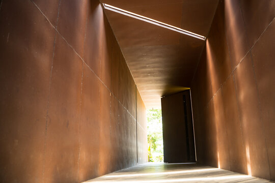Steel of rusty iron patterns with beams of sunlight and shadows within the tunnel throughout the day. At the end of the tunnel. Vintage modern design of building.