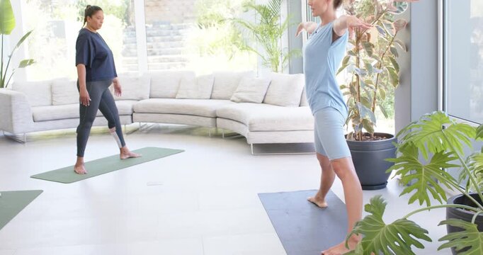 Diverse group following light-blue leader cue, holding warrior poses on mats in studio, copy space