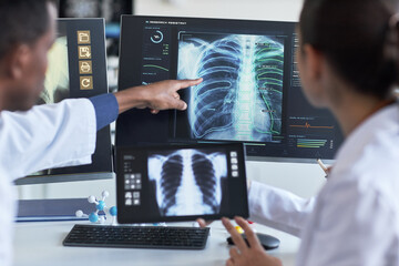 Doctors reviewing chest X ray scans on monitor and tablet, pointing at lung analysis for diagnosis and collaboration. Ideal for healthcare technology, radiology, AI diagnostics marketing © DragonImages