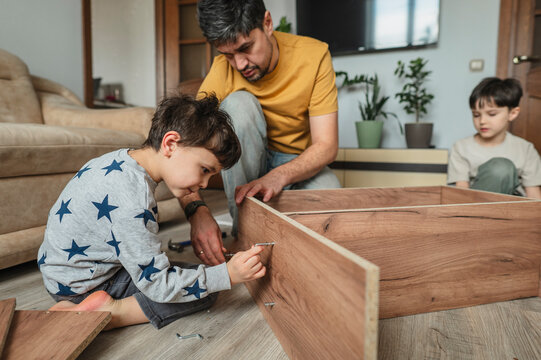 Father and children assembling furniture together at home