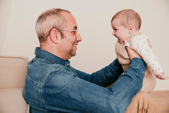 Father smiling and holding baby at home showing affection