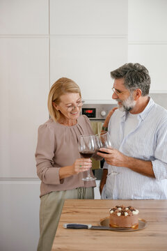 Couple toasting wine and celebrating at home with cake