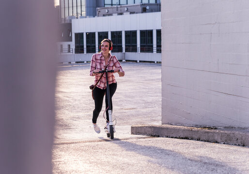 Smiling woman riding an electric scooter outdoors in a modern city
