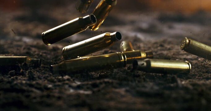 Slow Motion Of Close Up Of Bullet Shells Falling And Hitting Ground With Dust And Impact Particles. Concept Of Violence And War Aftermath. Conflict And After Battle Scene