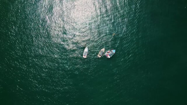 Several small fishing boats float closely together on the dark, rippling ocean surface off the coast of Peru during the day.