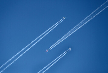 Planes leaving contrails against a clear blue sky © Tayiba Studio
