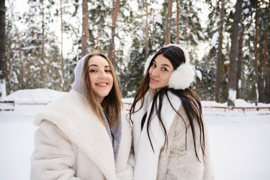 Smiling friends in warm winter clothes enjoying snowy outdoors