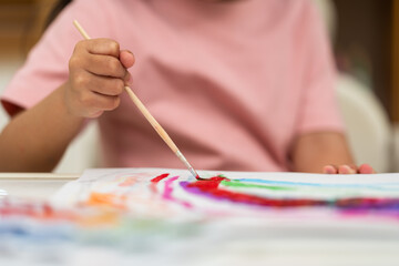 Naklejka premium close up of preschool child girl painting on paper with watercolor in pan